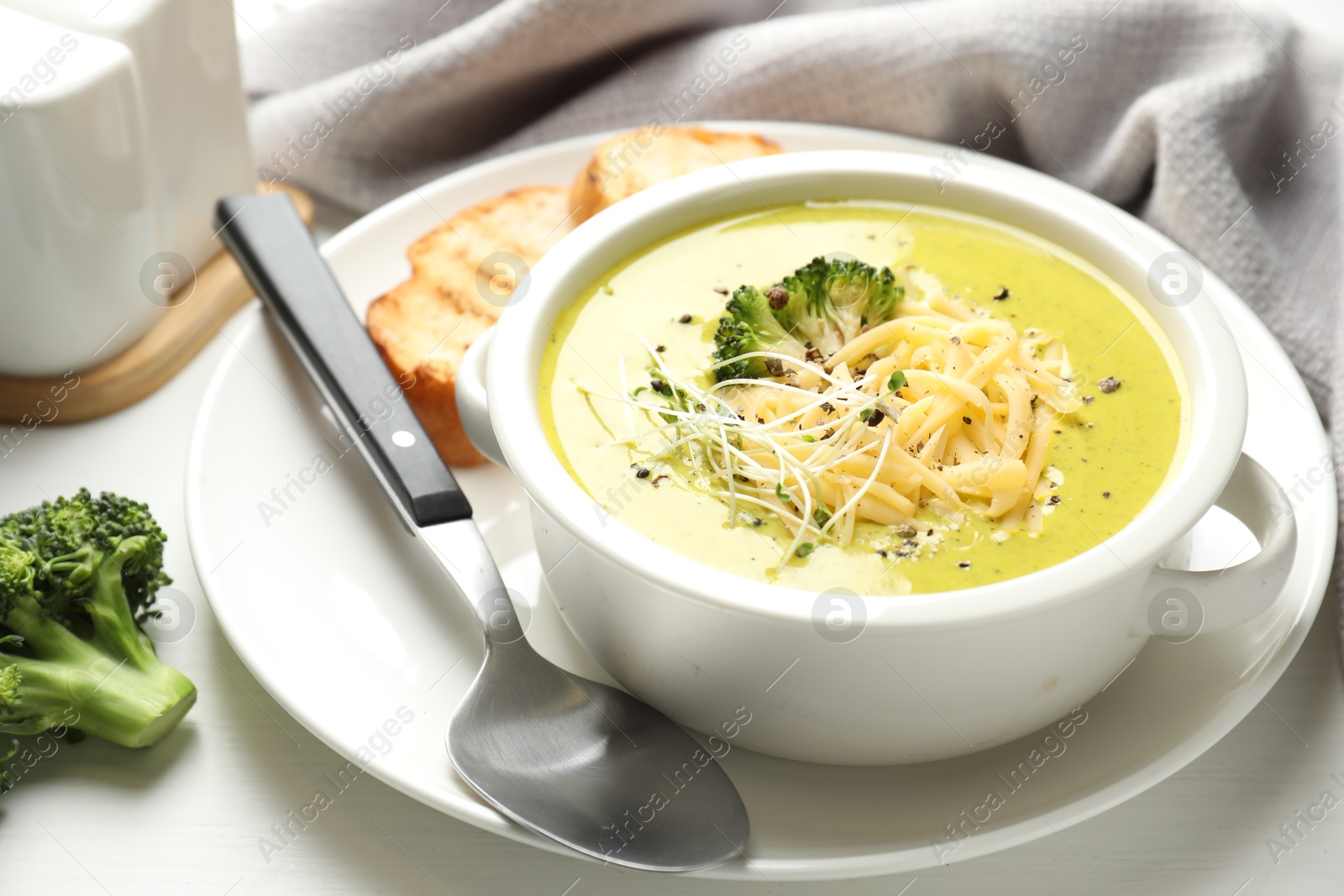 Photo of Delicious broccoli cream soup served on white wooden table, closeup