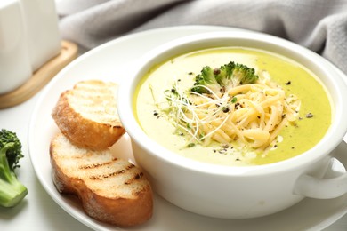 Photo of Delicious broccoli cream soup served on white table, closeup