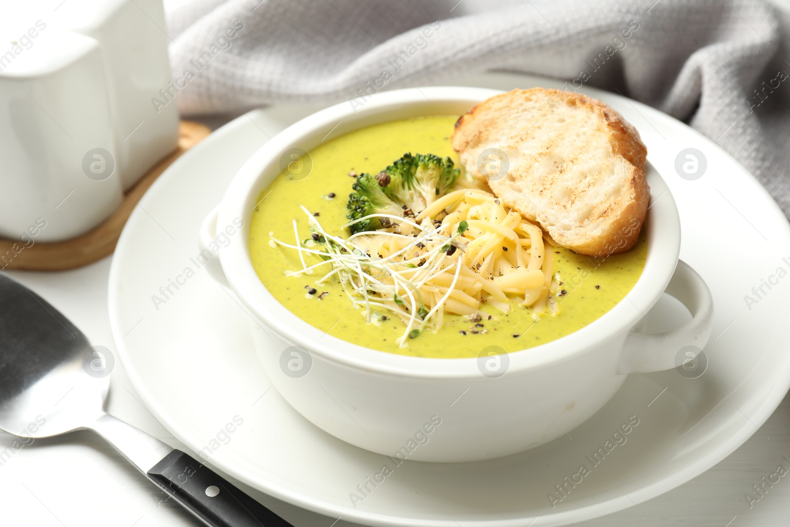 Photo of Delicious broccoli cream soup served on white table, closeup