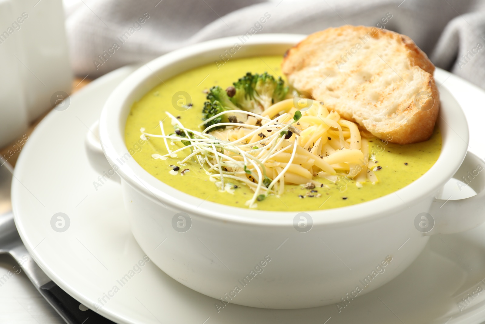 Photo of Delicious broccoli cream soup served on table, closeup