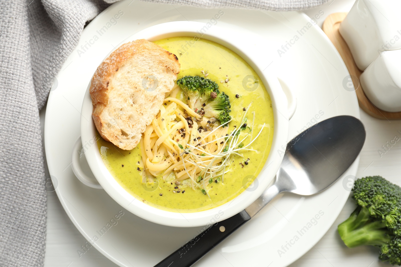 Photo of Delicious broccoli cream soup served on white table, flat lay