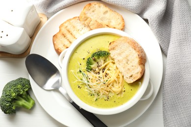 Photo of Delicious broccoli cream soup served on white table, flat lay