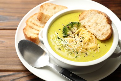 Photo of Delicious broccoli cream soup served on wooden table, closeup