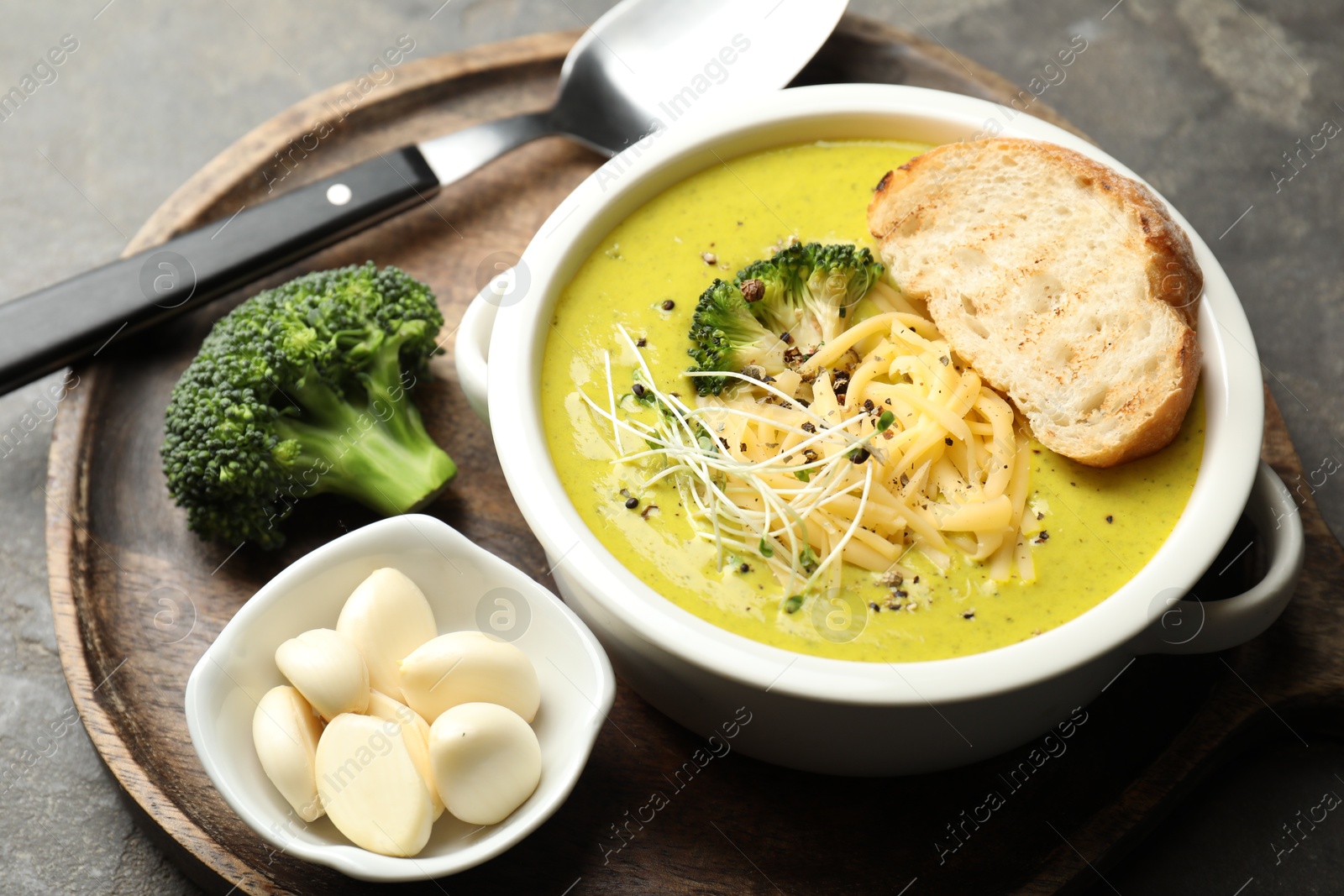 Photo of Delicious broccoli cream soup served on gray table, closeup