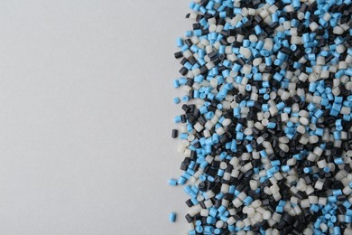 Photo of Pile of colorful plastic granules on grey background, top view. Space for text