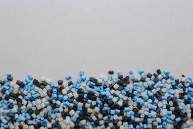 Pile of colorful plastic granules on grey background, top view. Space for text