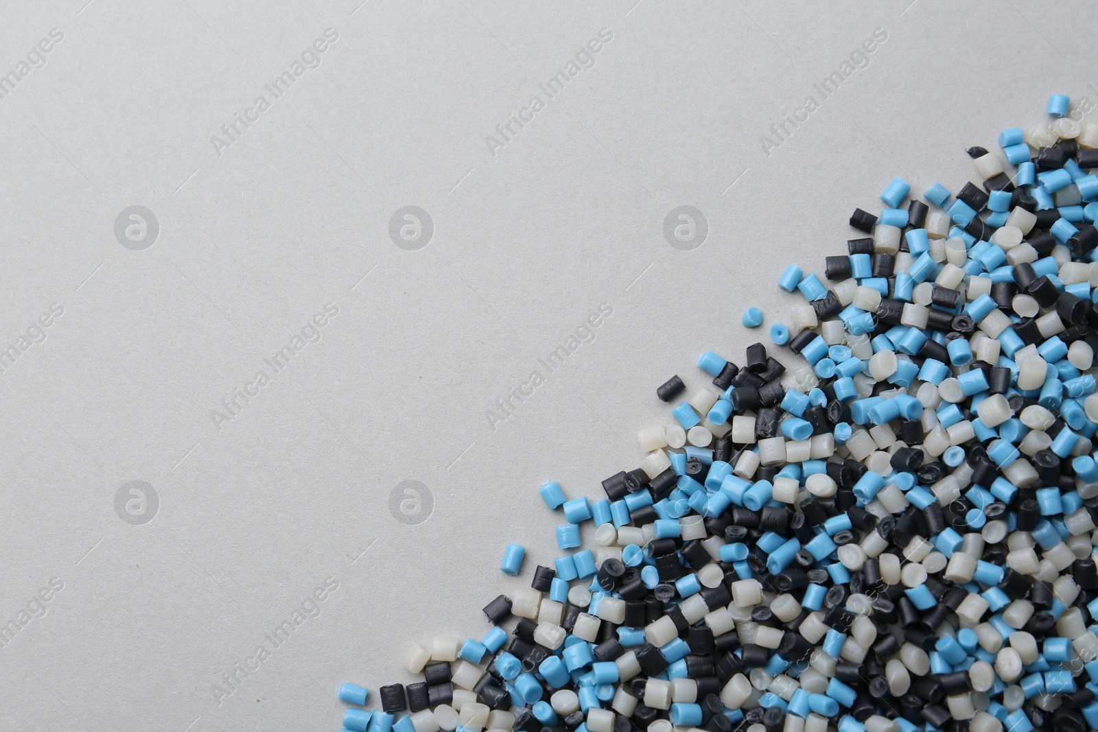 Photo of Pile of colorful plastic granules on grey background, top view. Space for text