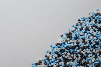 Photo of Pile of colorful plastic granules on grey background, top view. Space for text