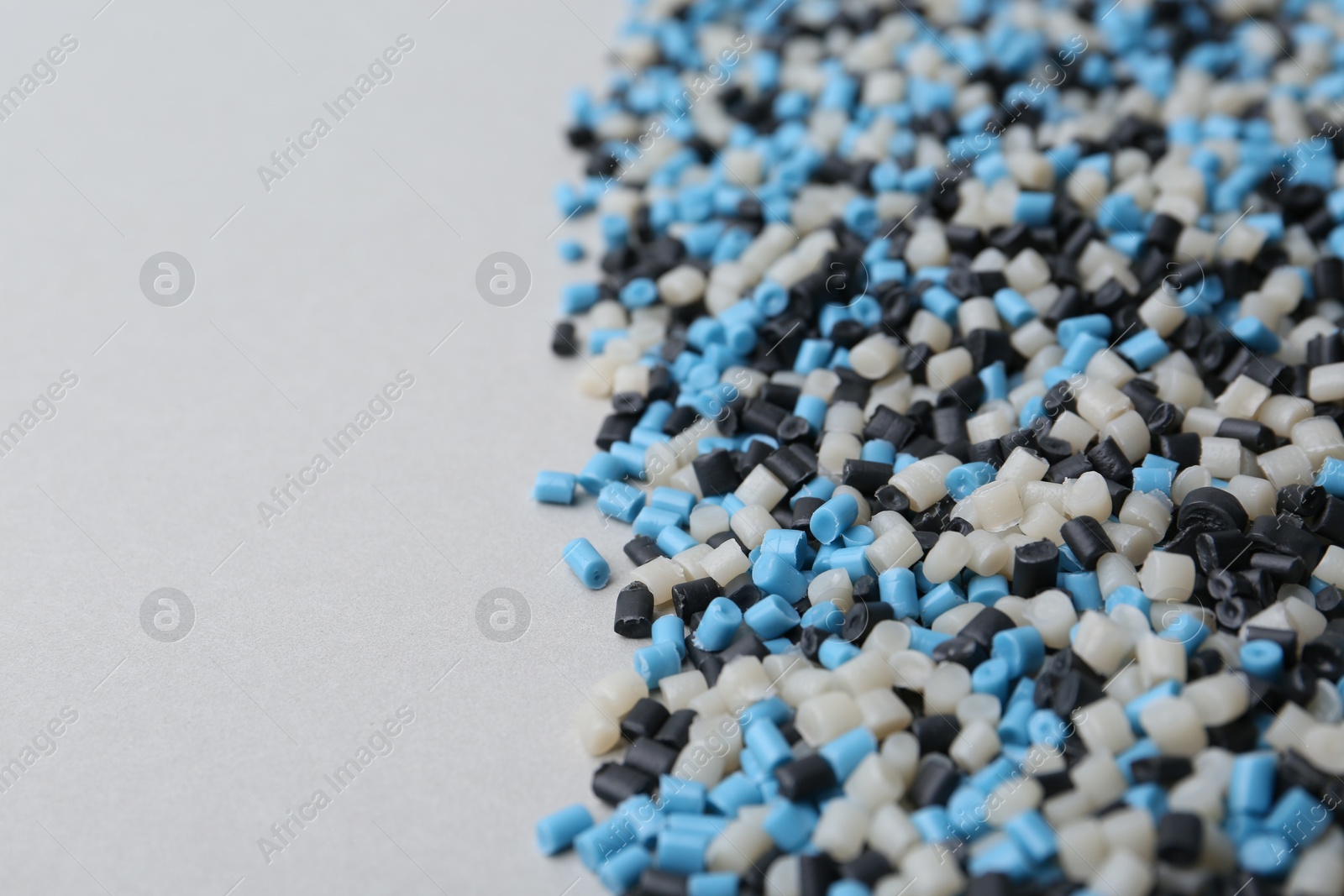 Photo of Pile of colorful plastic granules on grey background, closeup. Space for text