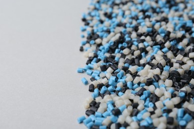 Pile of colorful plastic granules on grey background, closeup. Space for text