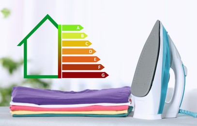 Image of Energy efficiency rating of home appliances. Iron and clean folded clothes on board indoors