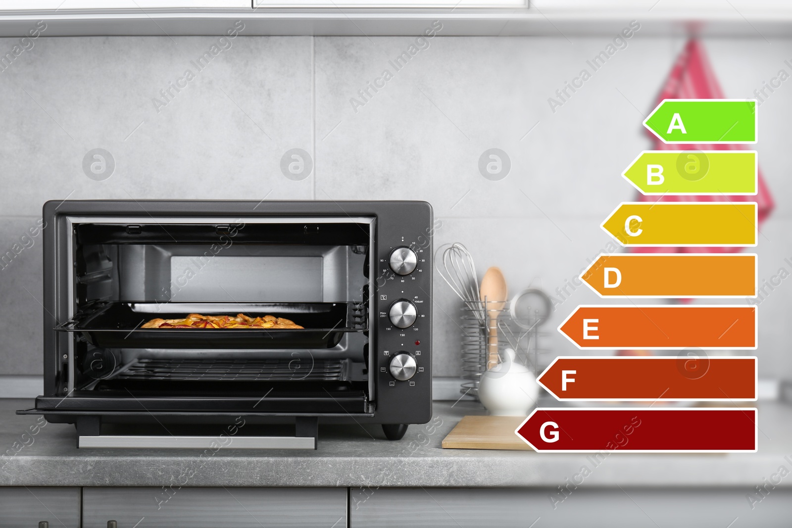 Image of Energy efficiency rating of home appliances. Electric oven with pie on countertop in kitchen