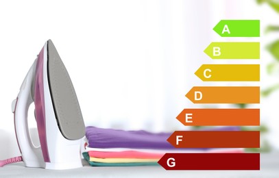 Image of Energy efficiency rating of home appliances. Iron and clean folded clothes on board indoors