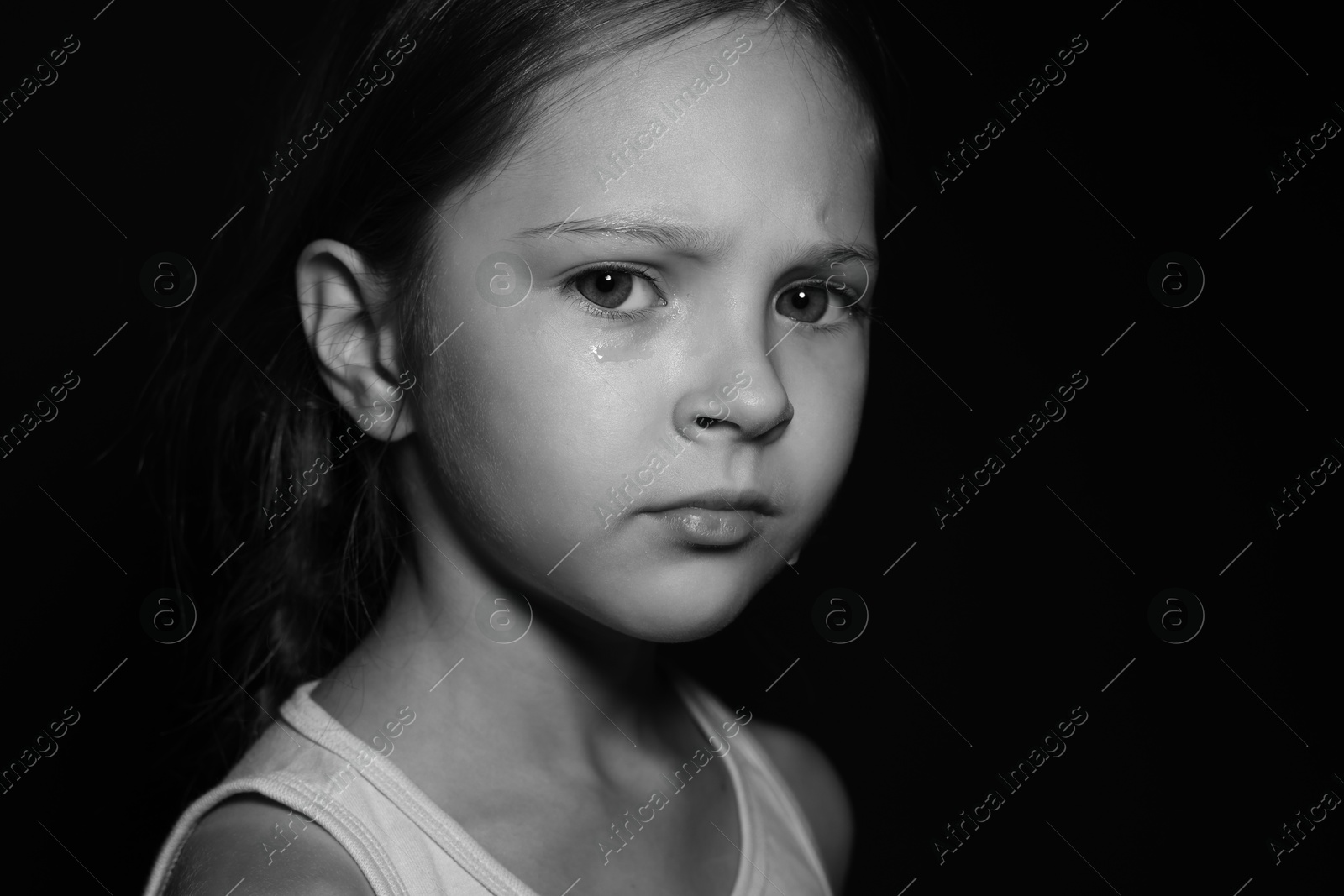 Photo of Orphanage concept. Sad girl on dark background. Black and white effect