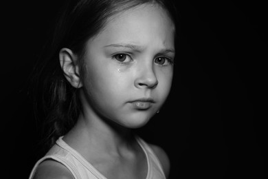 Photo of Orphanage concept. Sad girl on dark background. Black and white effect