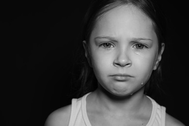 Photo of Orphanage concept. Sad girl on dark background, space for text. Black and white effect