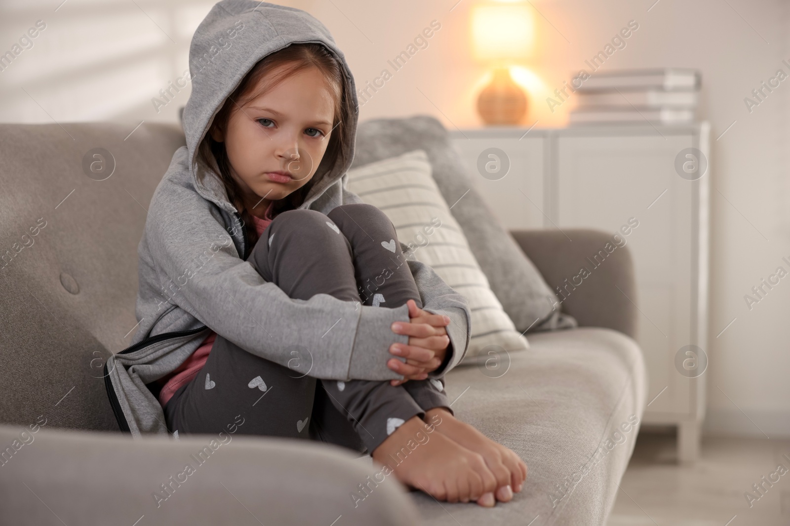 Photo of Orphanage concept. Sad girl sitting on sofa indoors