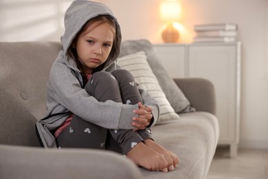 Photo of Orphanage concept. Sad girl sitting on sofa indoors