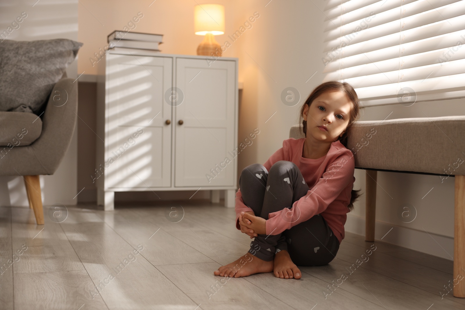 Photo of Orphanage concept. Sad girl sitting on floor indoors