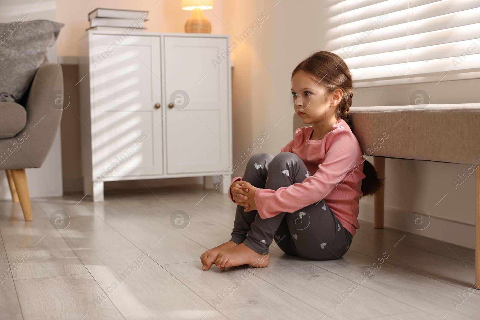 Photo of Orphanage concept. Sad girl sitting on floor indoors