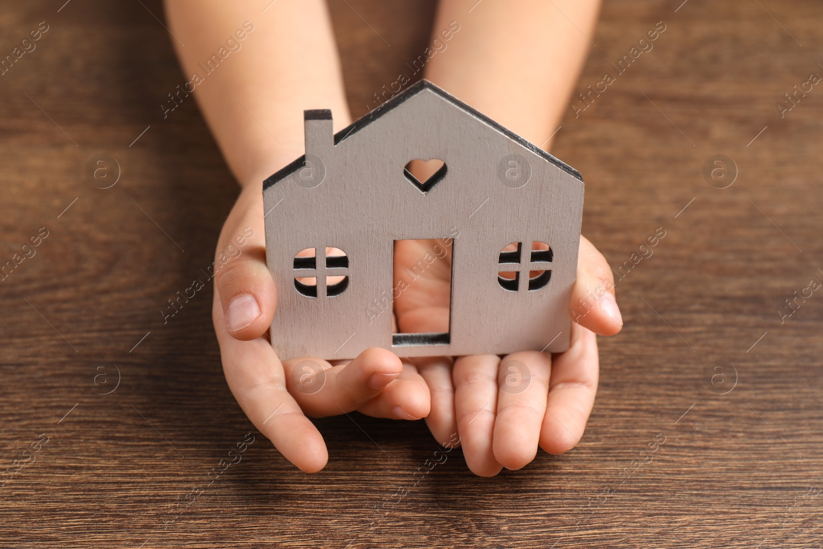 Photo of Adoption concept. Kid with cutout of house at wooden table, closeup