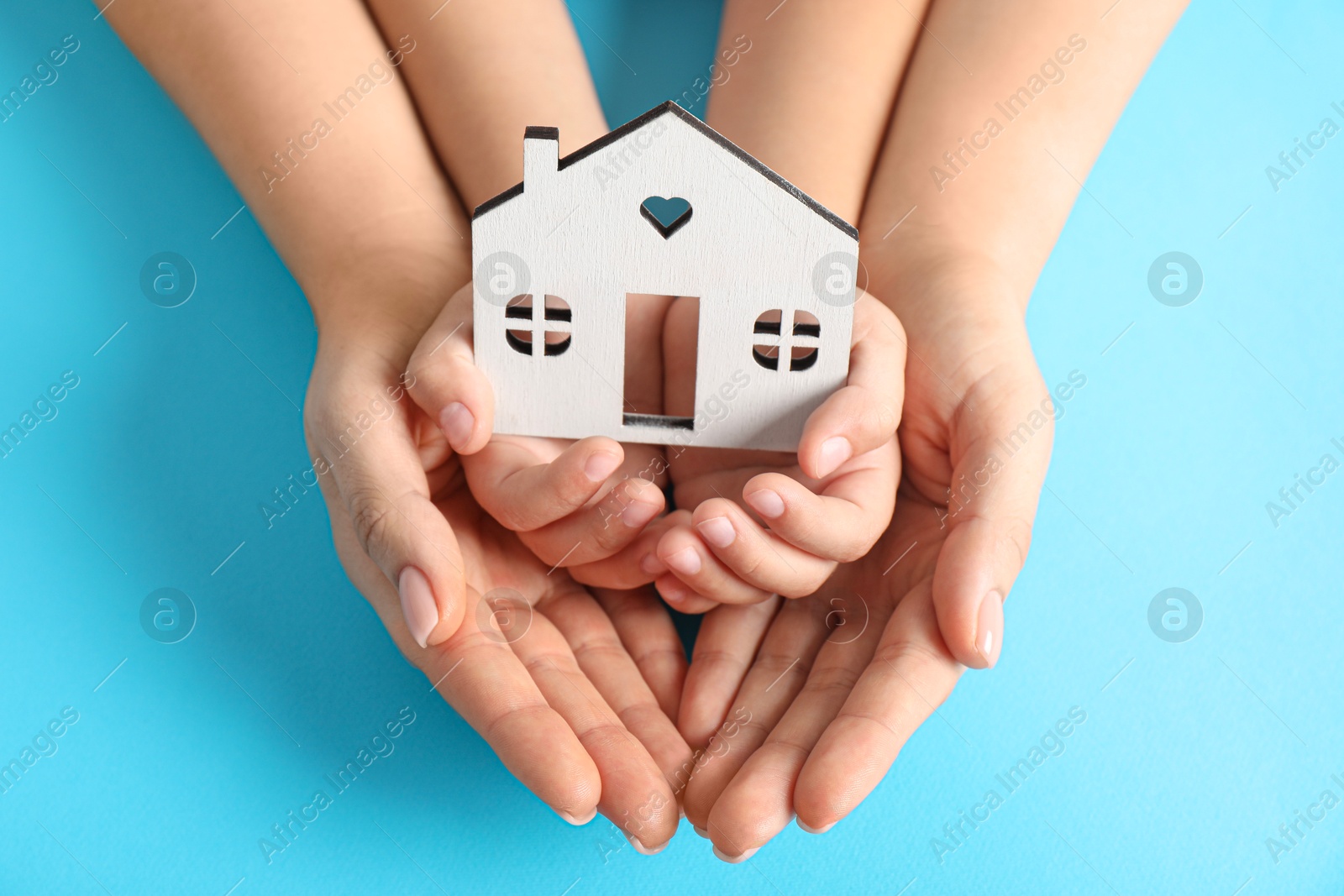 Photo of Adoption concept. Woman and kid with cutout of house at light blue background, top view