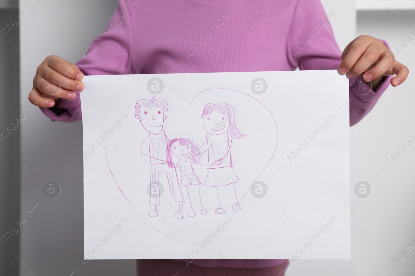 Photo of Adoption concept. Little girl holding drawing of family indoors, closeup