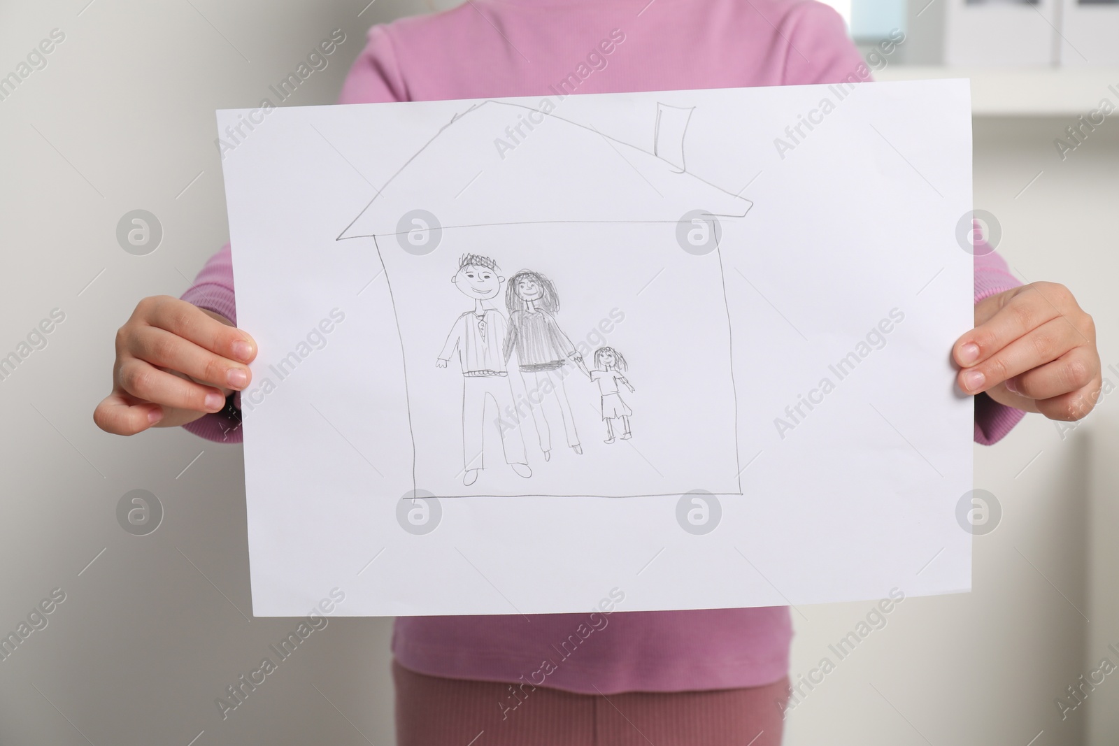 Photo of Adoption concept. Little girl holding drawing of family indoors, closeup