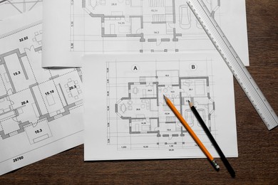 Photo of Different architectural drawings, ruler and pencils on wooden table, top view