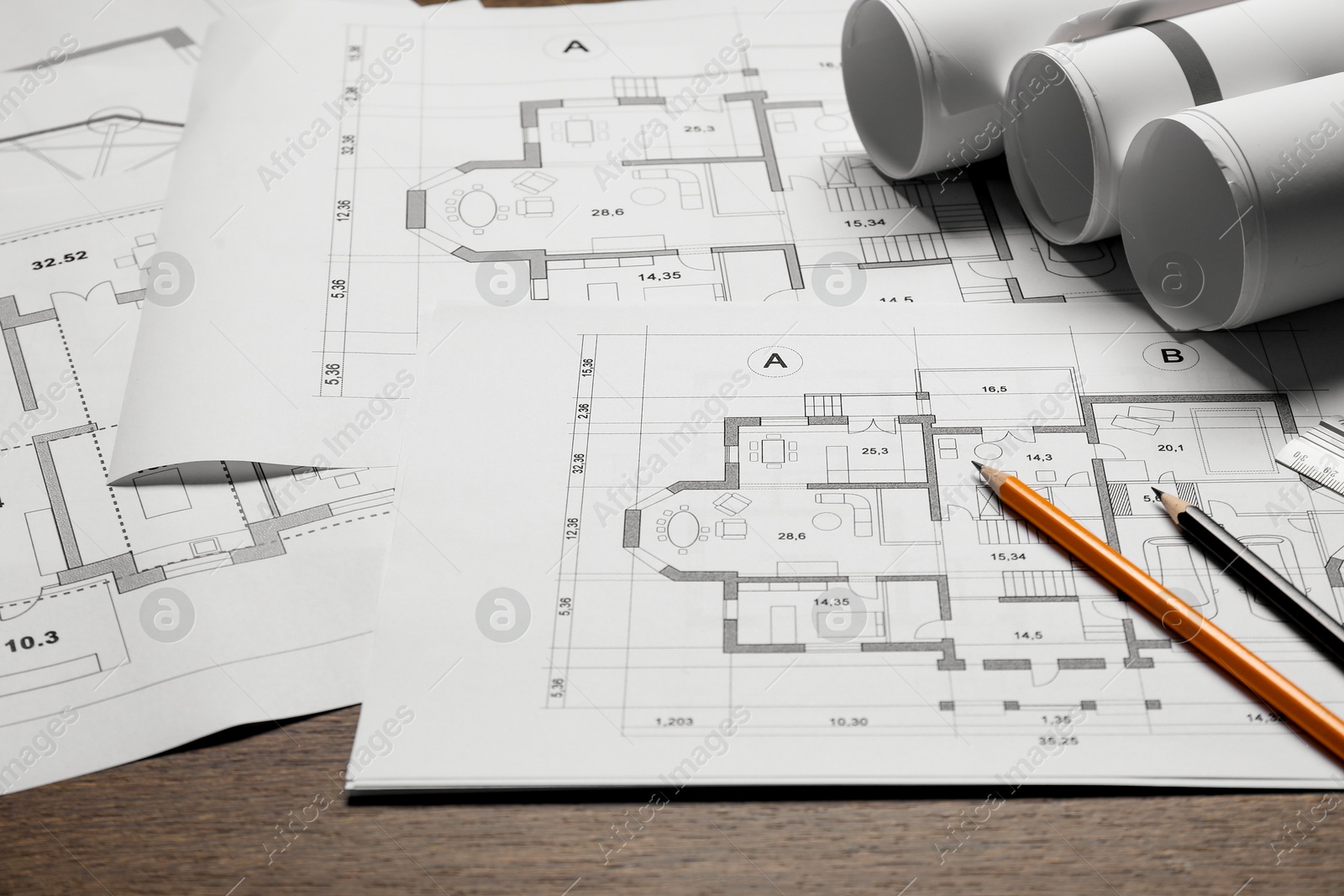 Photo of Different architectural drawings and pencils on wooden table, closeup