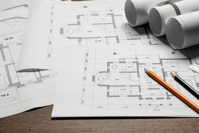 Photo of Different architectural drawings and pencils on wooden table, closeup