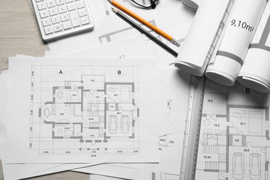 Photo of Different architectural drawings, calculator, ruler and pencils on wooden table, top view