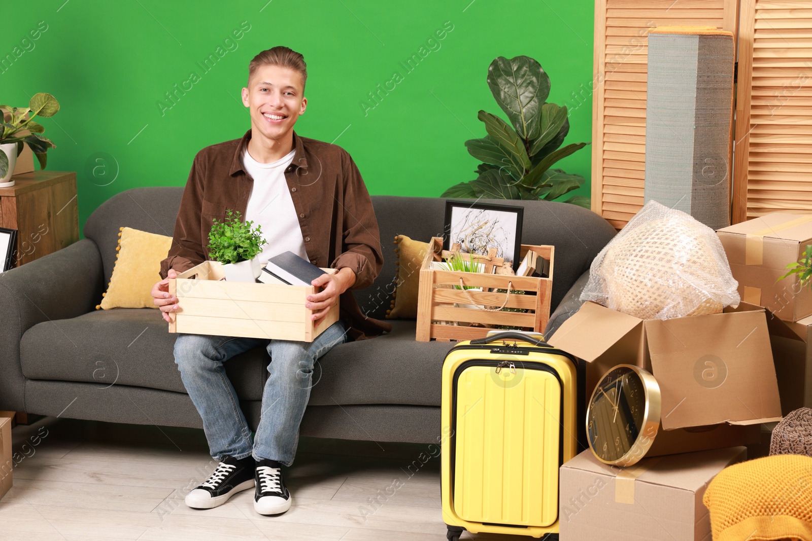 Photo of Happy man with different stuff in new apartment. Housewarming party