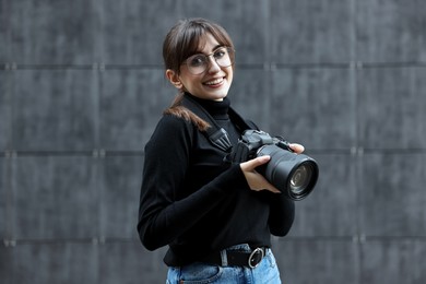 Photo of Professional photographer with digital camera near grey wall outdoors