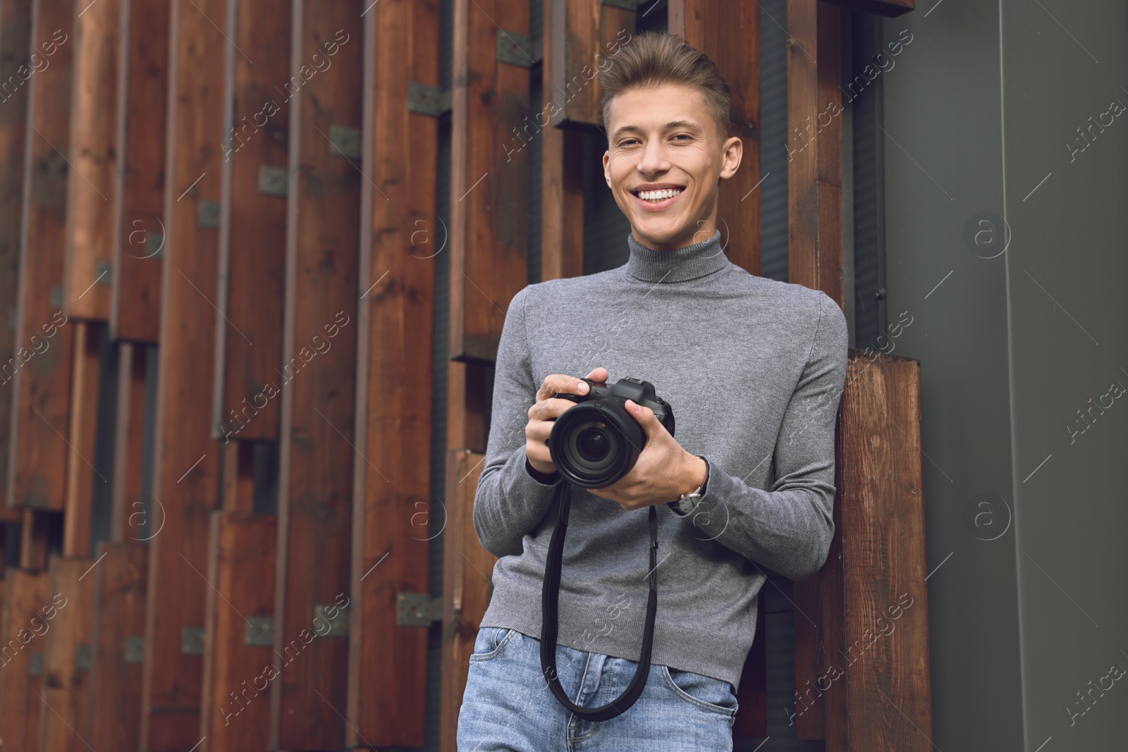 Photo of Professional photographer with modern camera near wall outdoors. Space for text