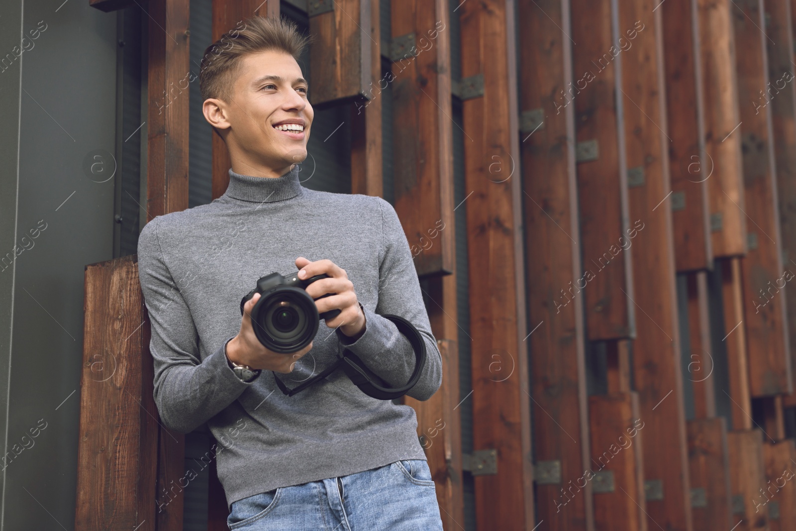 Photo of Professional photographer with modern camera near wall outdoors. Space for text