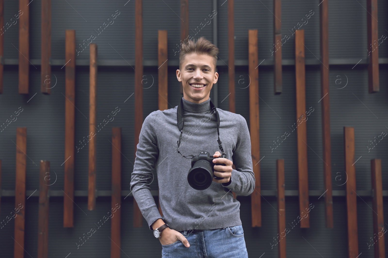 Photo of Professional photographer with modern camera near wall outdoors