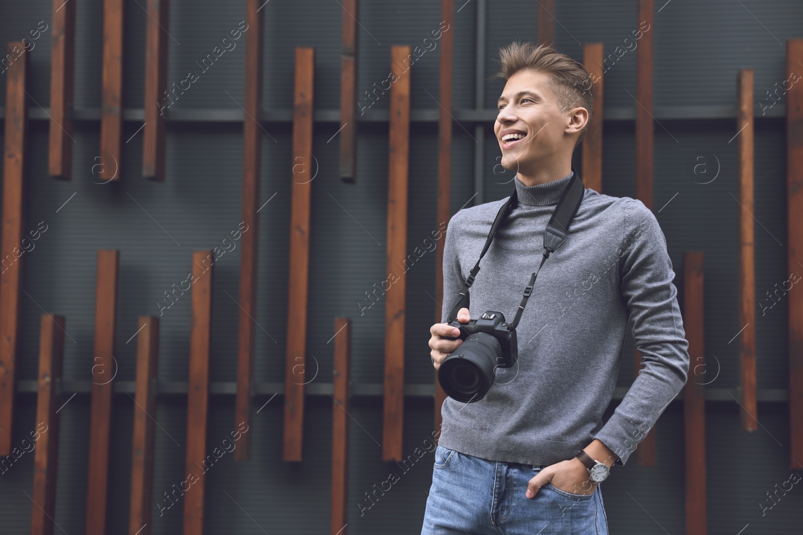 Photo of Professional photographer with modern camera near wall outdoors. Space for text