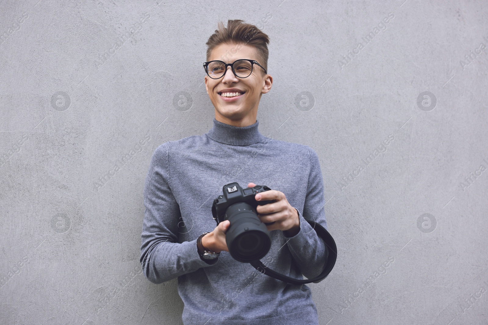 Photo of Professional photographer with camera near grey wall outdoors