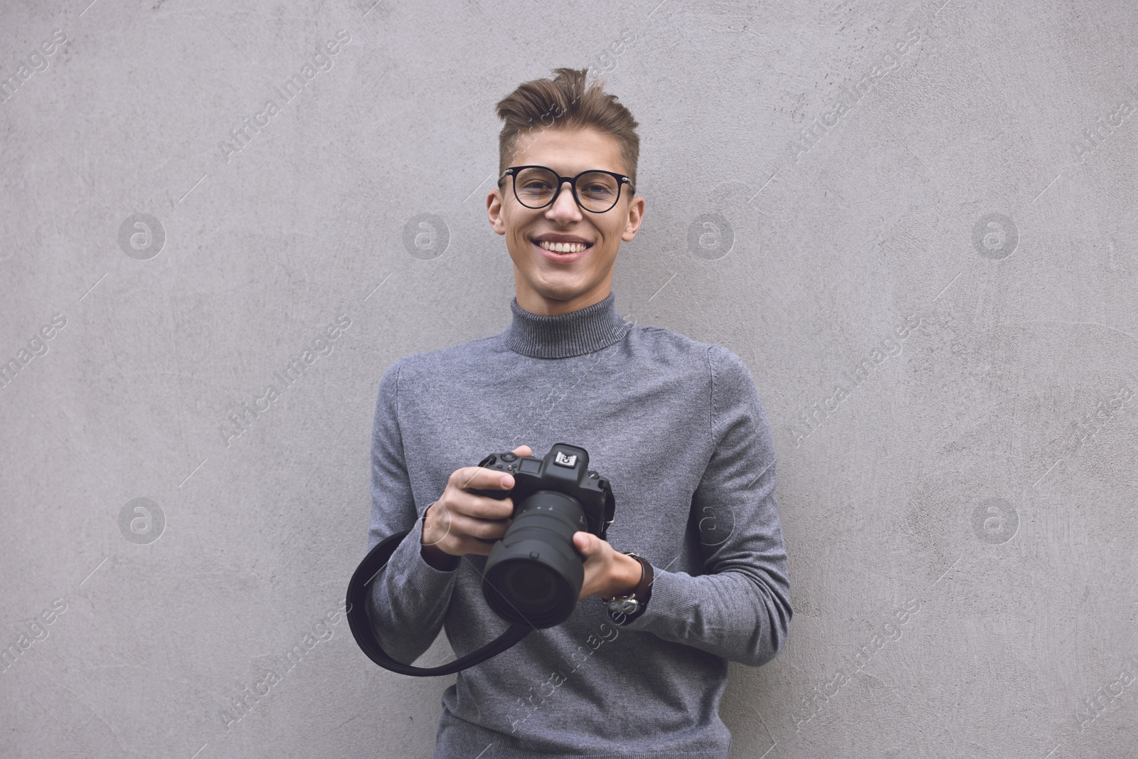 Photo of Professional photographer with camera near grey wall outdoors