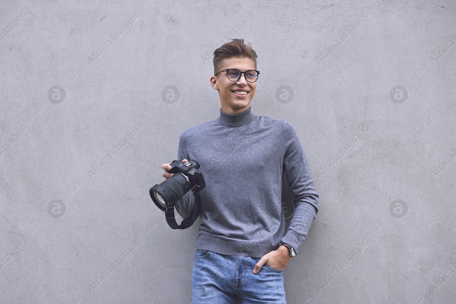 Photo of Professional photographer with camera near grey wall outdoors