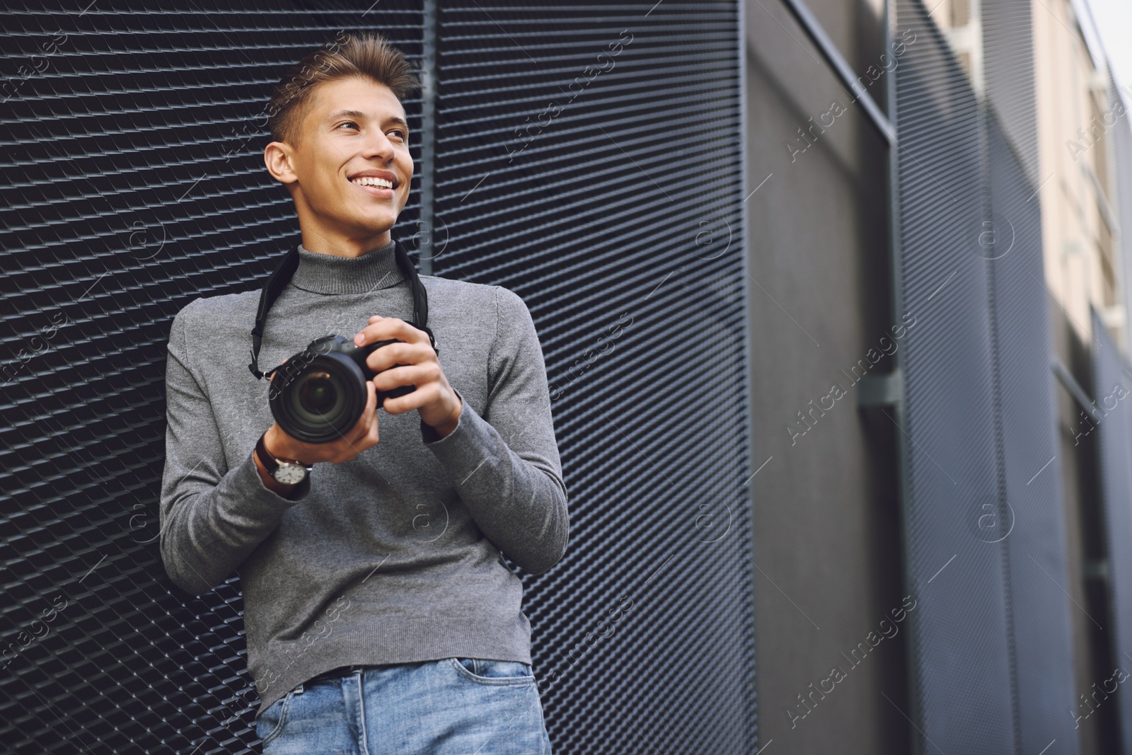 Photo of Professional photographer with modern camera near wall outdoors. Space for text