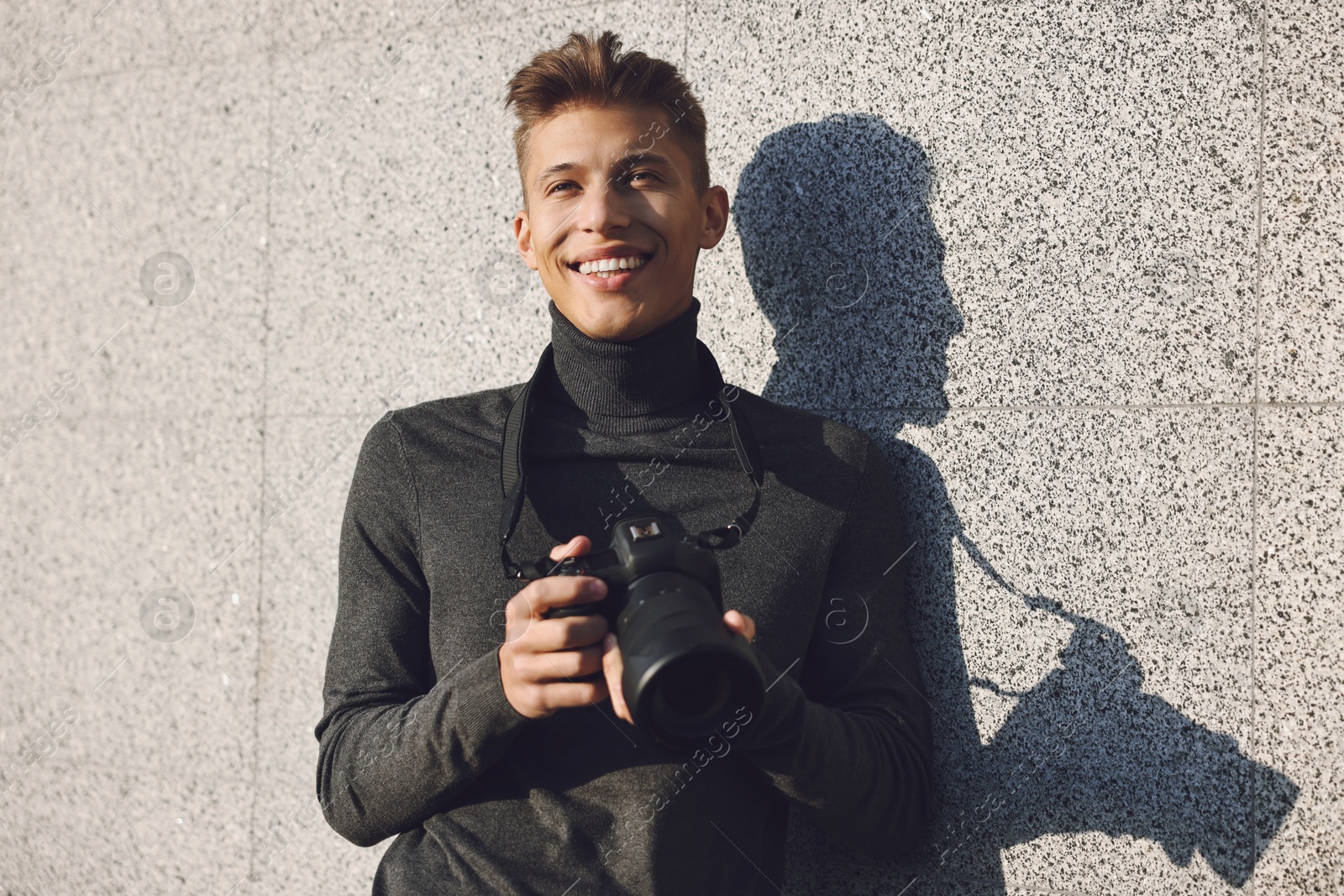 Photo of Professional photographer with modern camera near wall outdoors