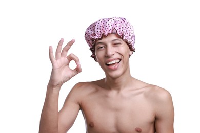 Photo of Happy man in pink shower cap showing ok gesture on white background