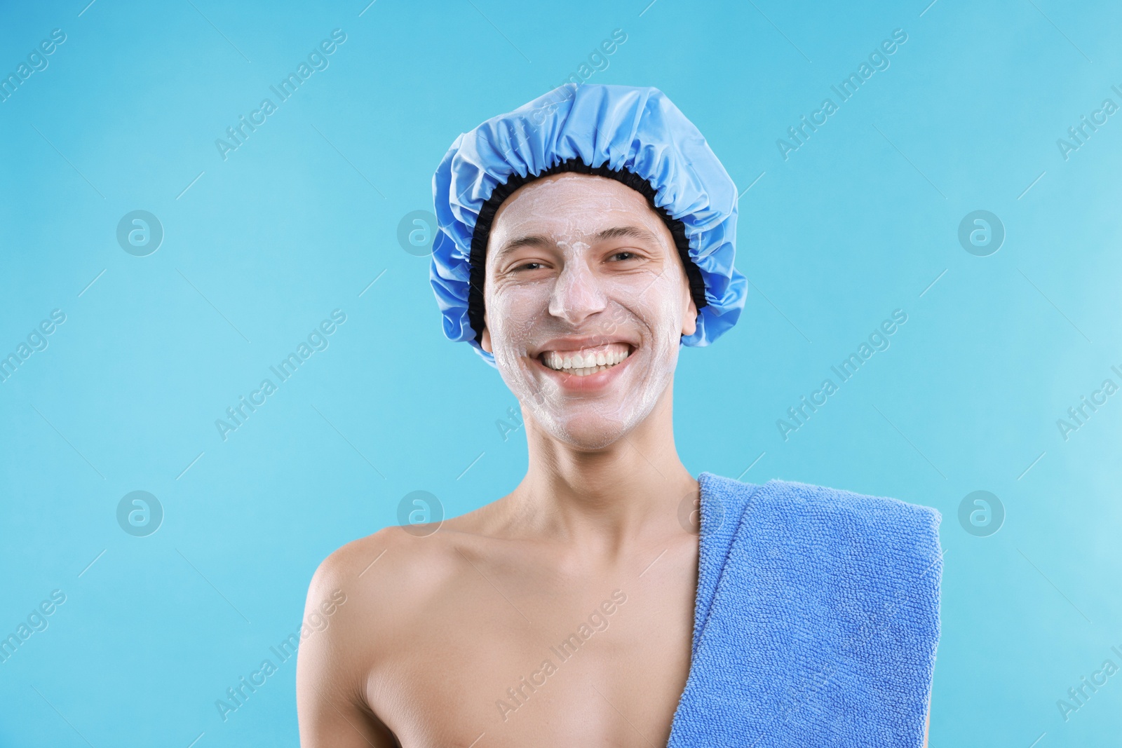 Photo of Man in shower cap with cream on his face against light blue background