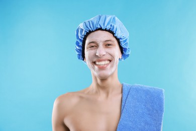 Man in shower cap with cream on his face against light blue background