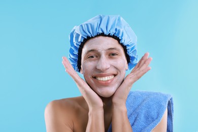 Photo of Man in shower cap with cream on his face against light blue background