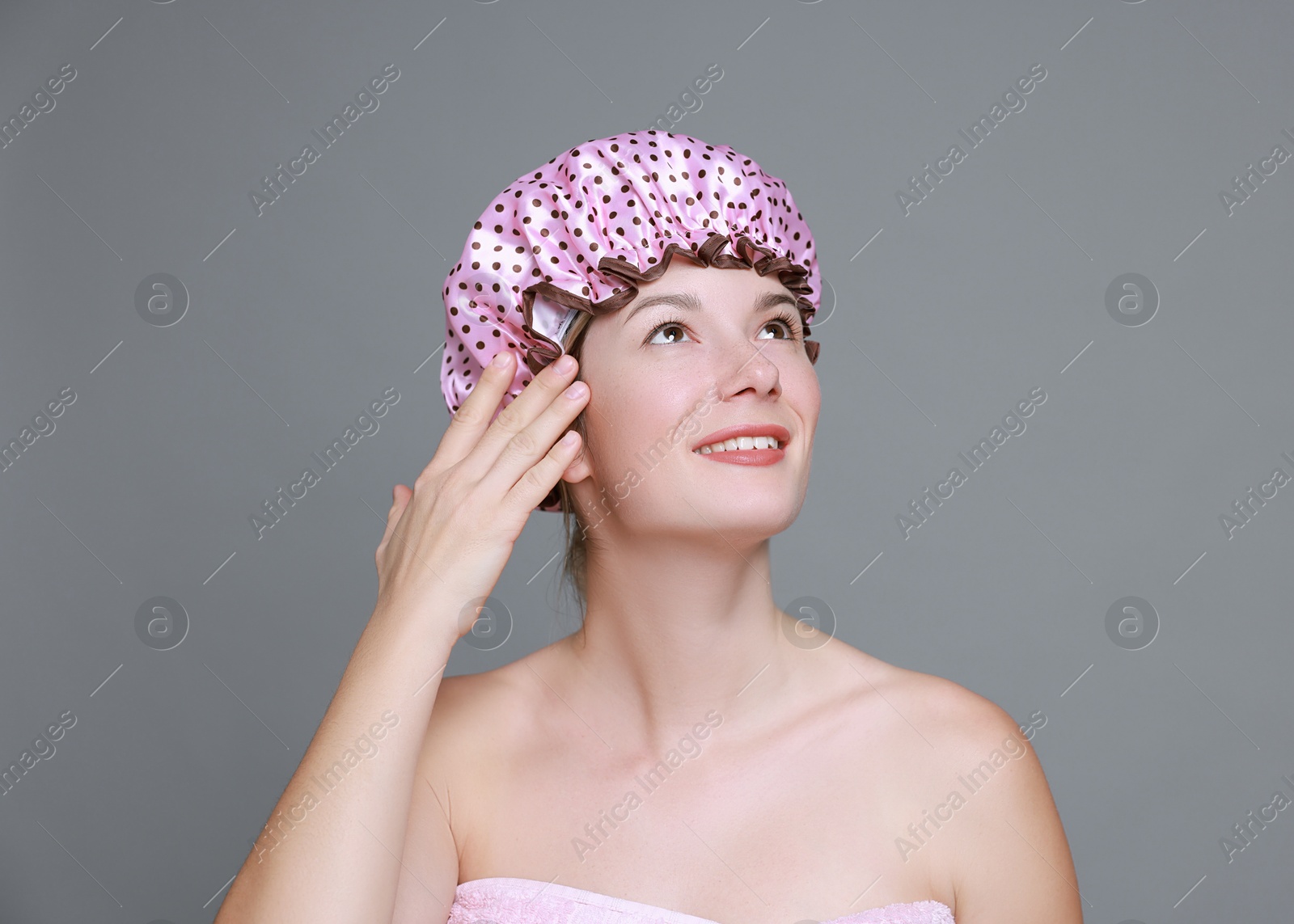 Photo of Happy woman in shower cap on grey background