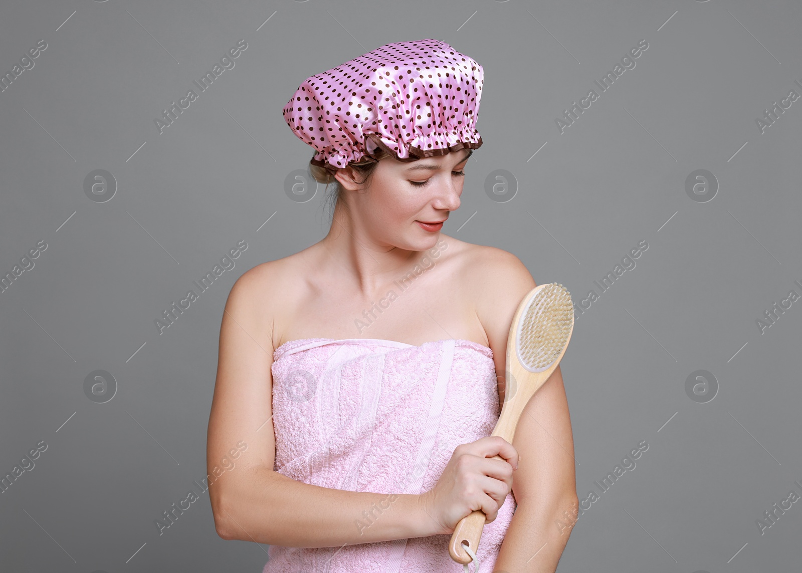 Photo of Woman with shower cap and brush on grey background