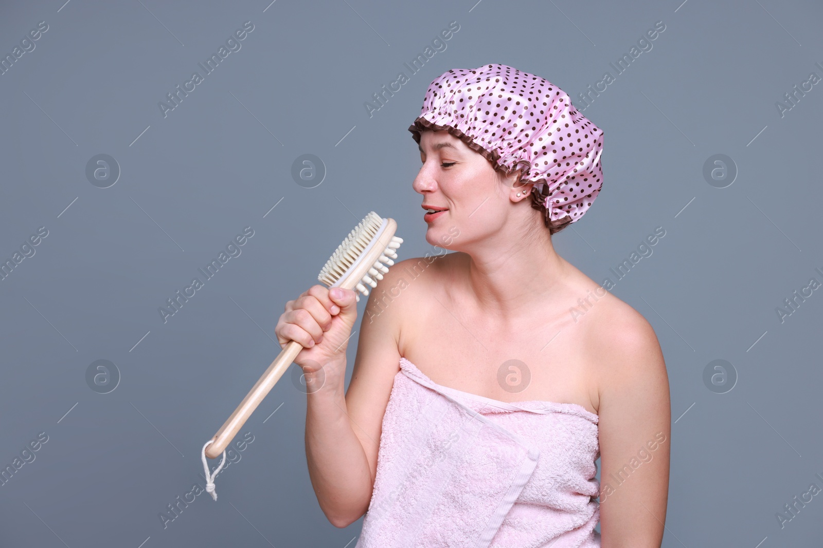 Photo of Woman with shower cap and brush singing on grey background